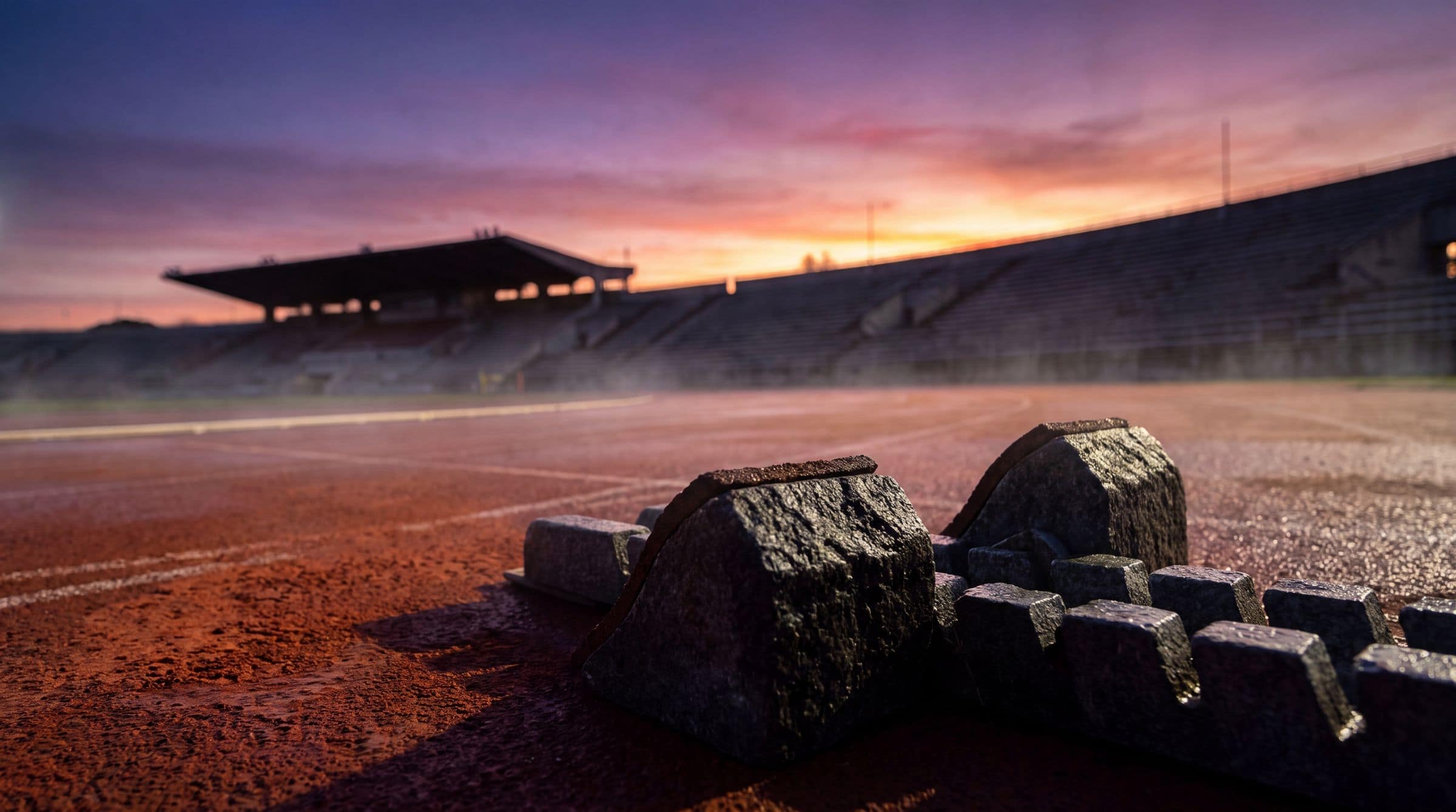 Starting blocks on a running track under a dawn sky